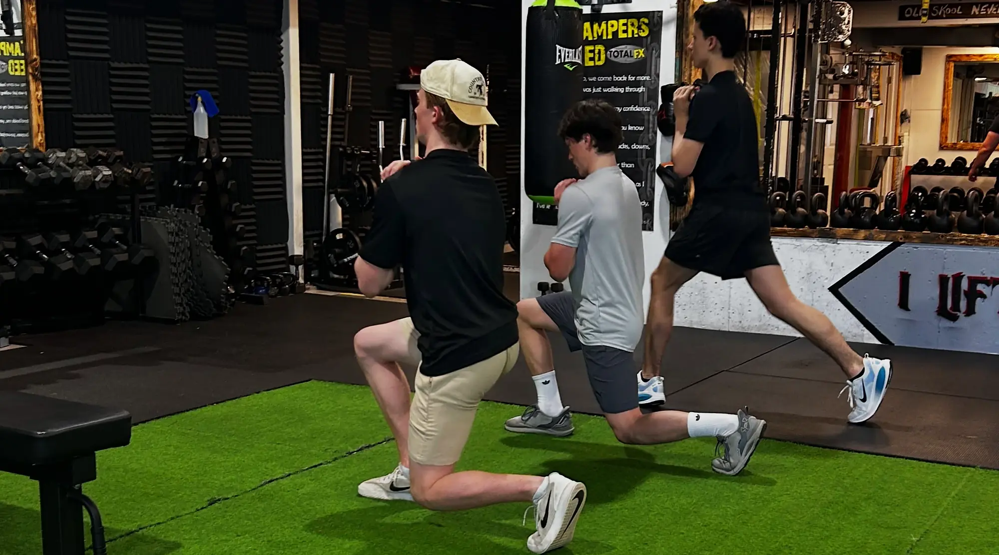 Three athletes doing split squats on the turf during a session at K2 Athletics in Charlottetown